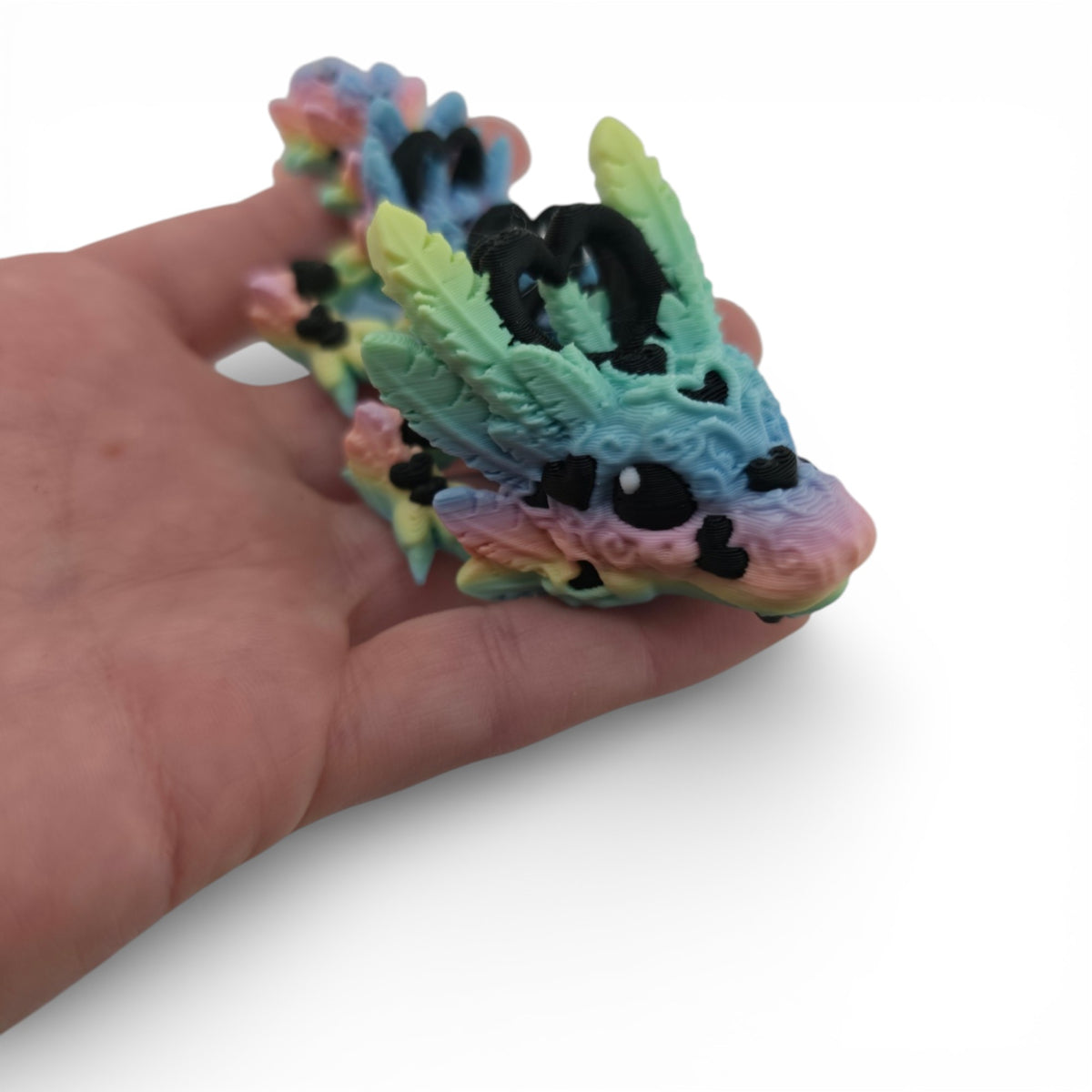 Pastel Rainbow and Black Light Heart Baby Dragon held in hand for scale